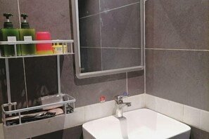 Bathroom features a large sink, mirror, and storage shelf.