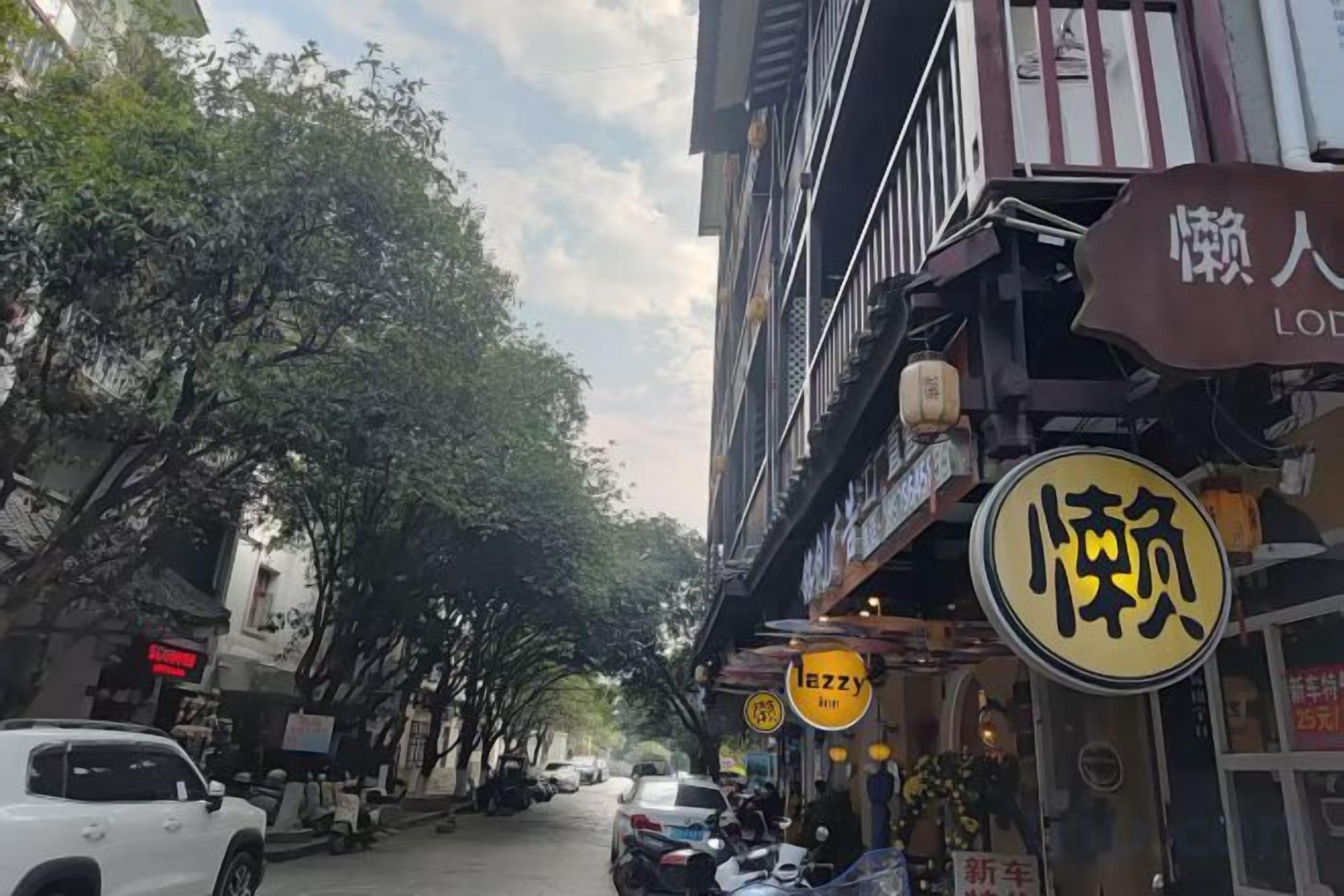 Una calle con edificios, un letrero de restaurante y coches estacionados.
