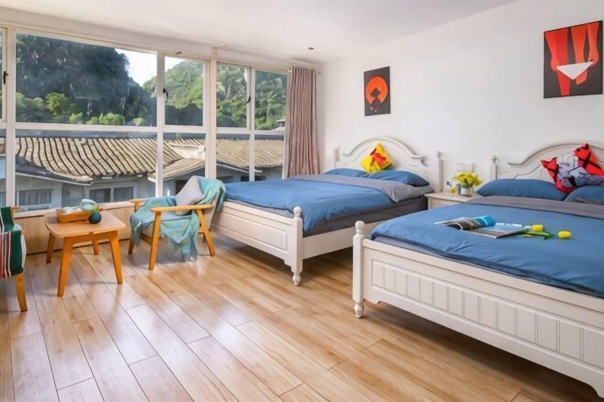 A bedroom with two beds, a window, and a view of a traditional roof.