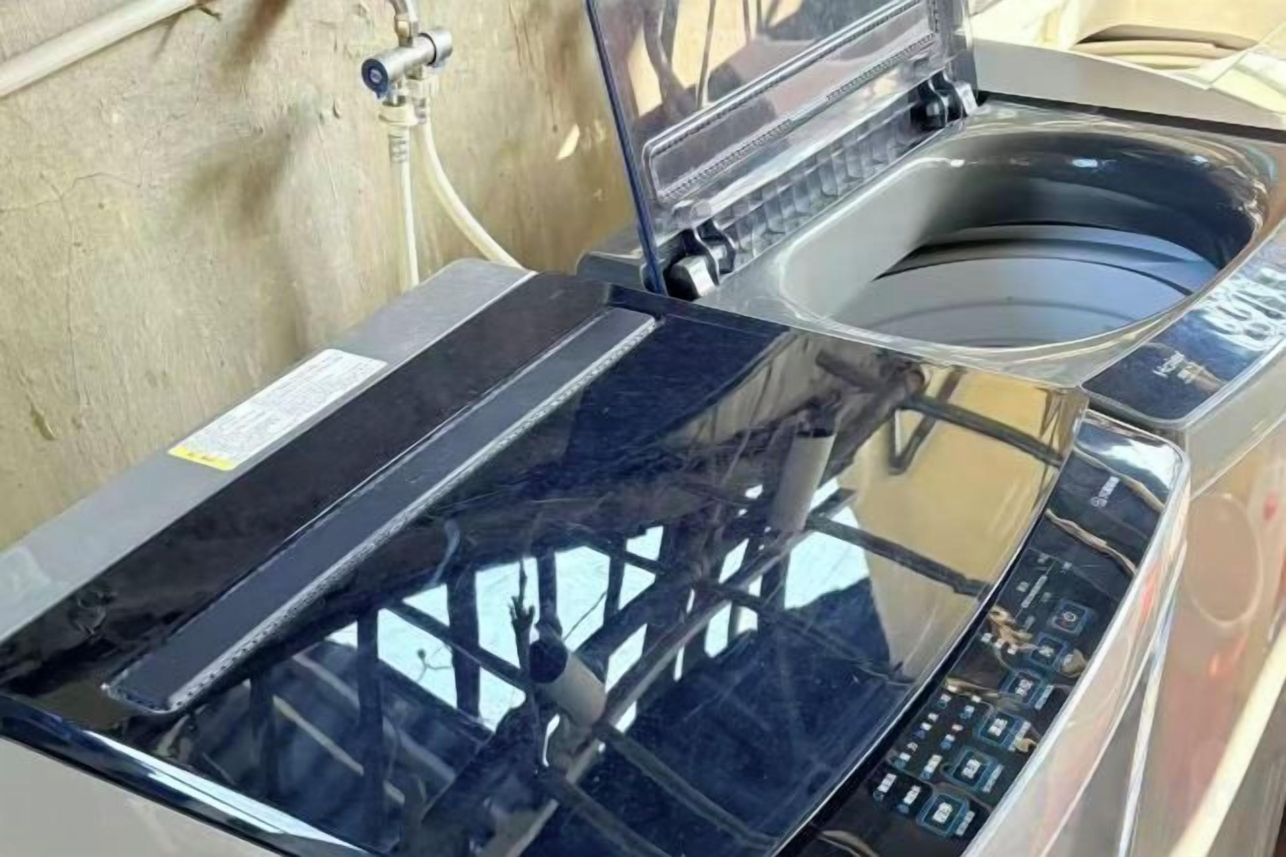 A washing machine with a transparent door, control panel, and a water inlet hose.