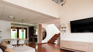 Una sala de estar moderna con un sofá, una mesa redonda de centro y una escalera que sube a un nivel superior.