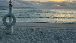 Une bouée de sauvetage fixée à un poteau, sur lequel est apposé un numéro, sur une plage.