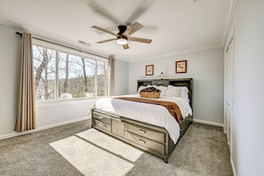 A bedroom with a bed, a ceiling fan, a window with curtains, and a view of trees outside. - Lakefront Cabin Retreat w/ Dock in Robbinsville! (Robbinsville)
