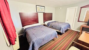 A hotel room with two beds, a red curtain, a framed picture on the wall, and a striped carpet.