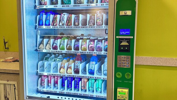 A vending machine with multiple shelves stocked with snacks, drinks, and other items.