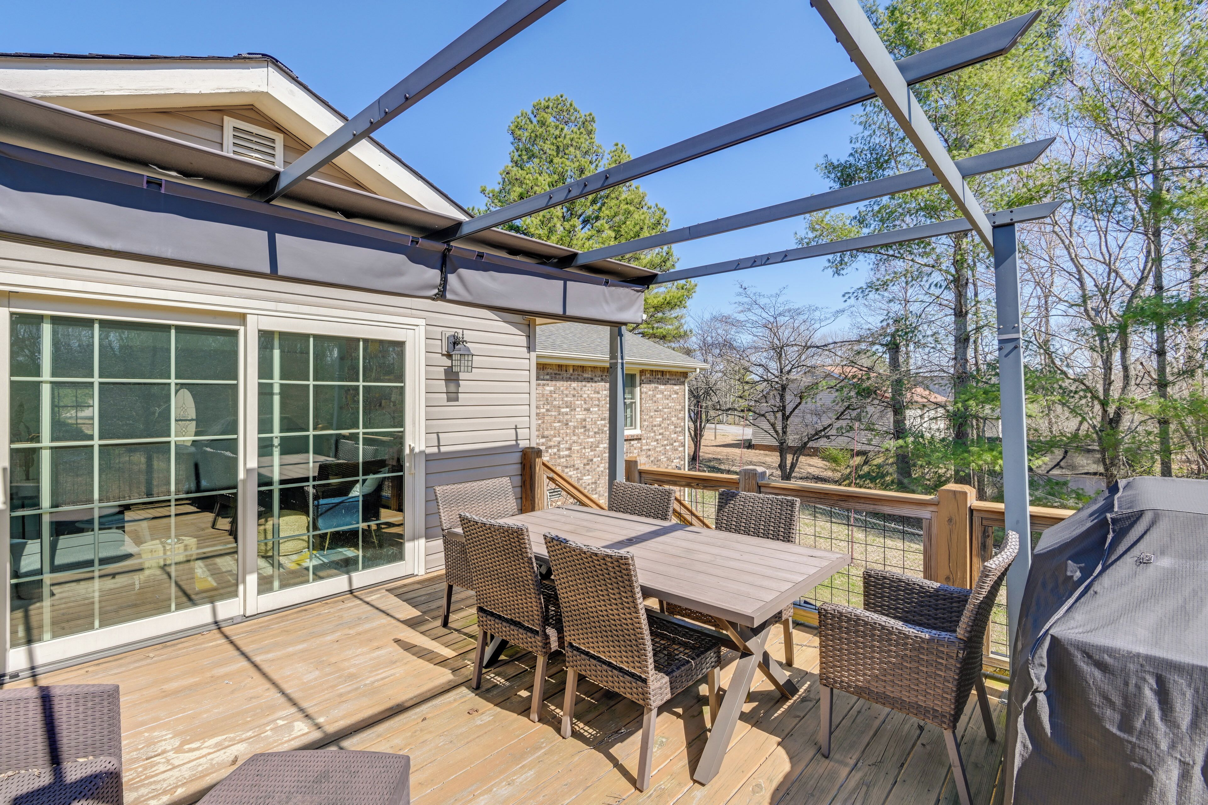 An outdoor deck with a dining table, chairs, and a grill.