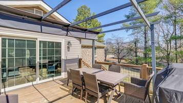 An outdoor deck with a dining table, chairs, and a grill.