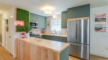 A modern kitchen with a central island, stainless steel appliances, and a green accent wall.