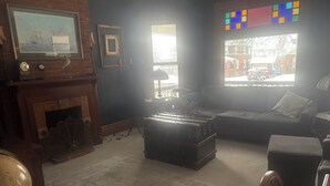 Ein Wohnzimmer mit Kamin, einer Couch, einem Couchtisch und einem Fenster mit Blick auf die Straße.