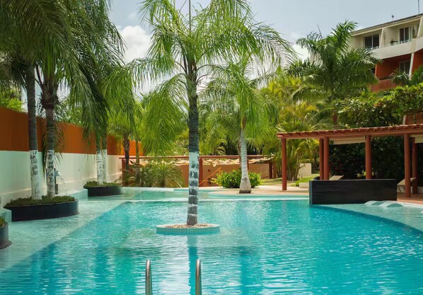 Relax by the serene pool surrounded by lush greenery and palm trees.