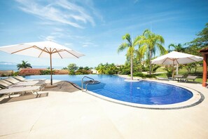 Relax by the serene pool surrounded by lush greenery and ocean views.