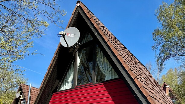 A modern house with a red roof, large windows, and a satellite dish. - Pure nature - forest vacation in a tiny house (Ronshausen)