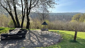 A picnic area with a bench and a table, surrounded by trees and a grassy field. - Pure nature - forest vacation in a tiny house (Ronshausen)