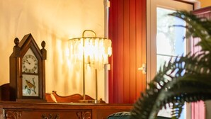 En hyggelig stue med et træskab, en grøn sofa med en hvid pude, et ur og en lampe.