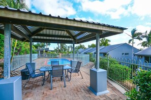 A covered outdoor area with a pool, patio furniture, and a fenced poolside.