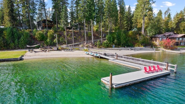 A lakeside dock with red chairs and a wooden pier extending into clear green water. - Beautiful Waterfront Cabin with a Hot Tub & Sauna (Nordman)