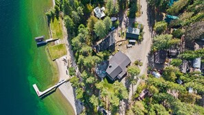 An aerial view of a lakeside property with multiple houses, a dock, and a grassy area. - Beautiful Waterfront Cabin with a Hot Tub & Sauna (Nordman)