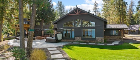 A modern house with a stone facade, large windows, and a well-maintained lawn.