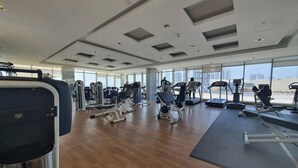 Ett rymligt gym med olika typer av träningsutrustning, stora fönster och en modern takdesign.