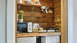 A compact kitchenette with a microwave, coffee maker, and a small stove.