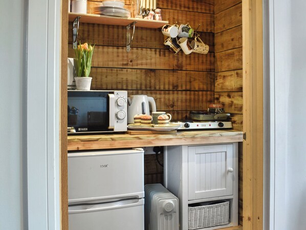 A compact kitchen with a microwave, coffee maker, and a small stove.