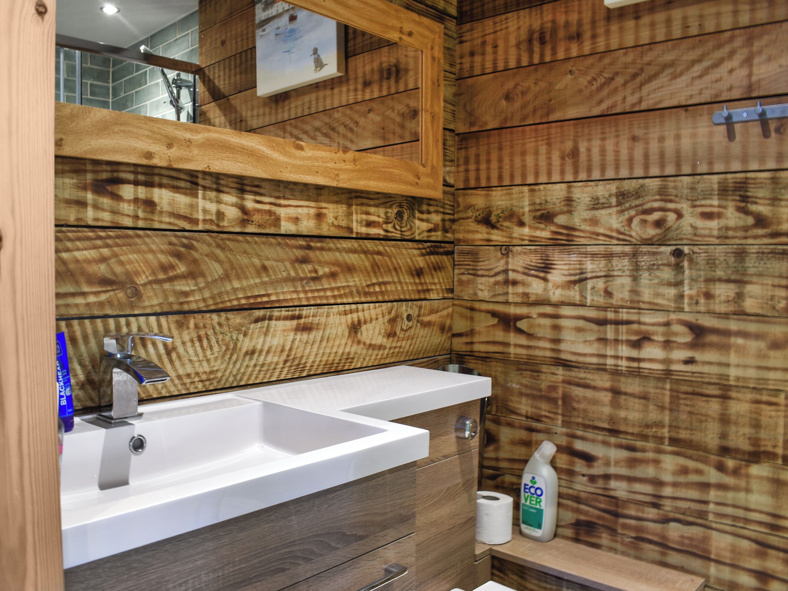 A bathroom with wooden paneling, a white sink, and a mirror.