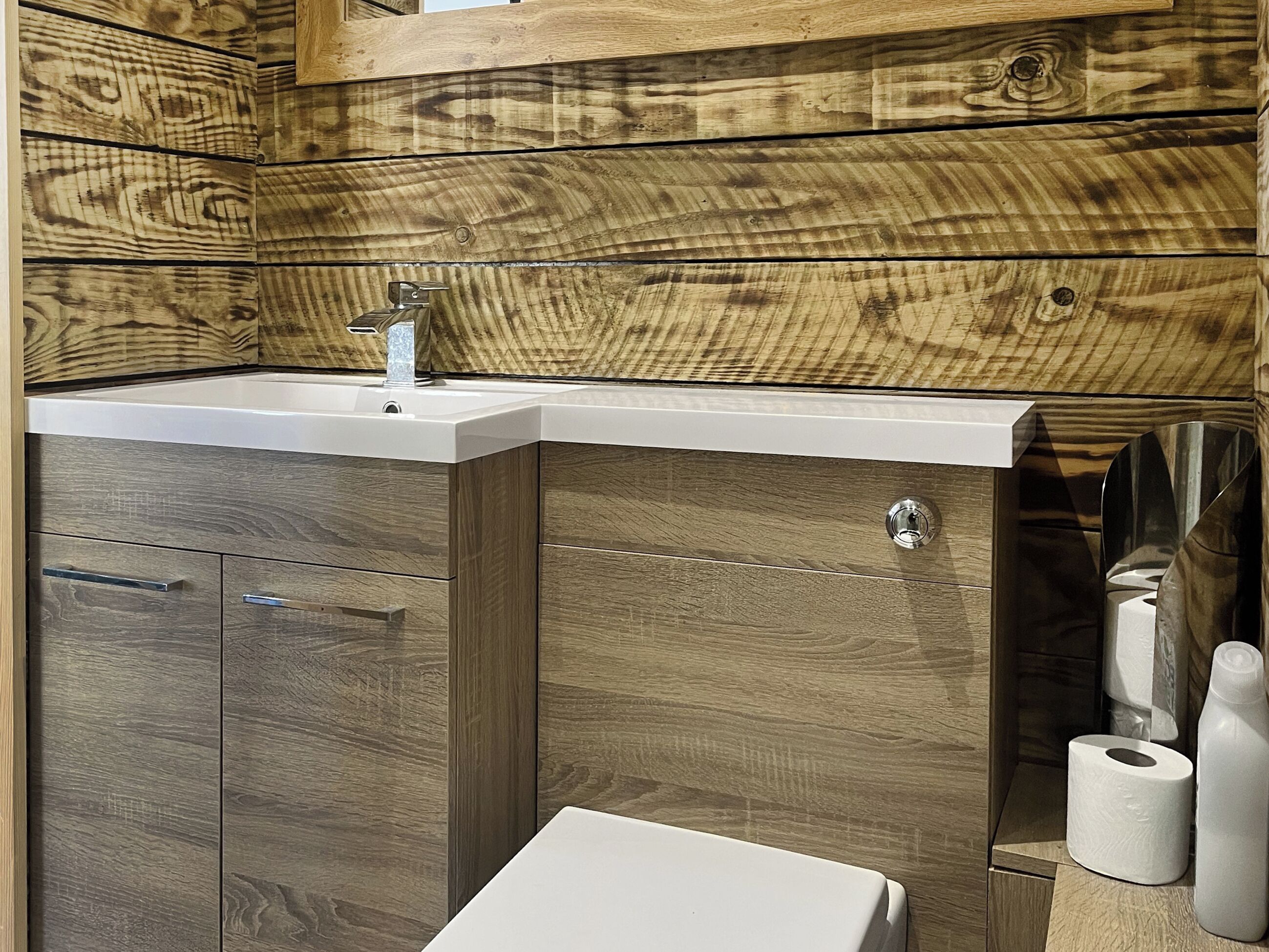 A bathroom with a wooden wall, a white sink, and a toilet.