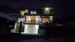 Uma casa moderna de dois andares com varanda, escadaria e entrada bem iluminada.