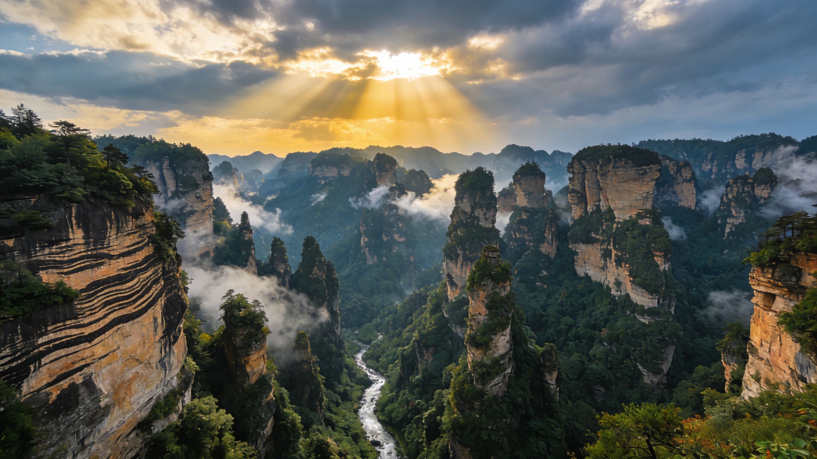 A mountainous landscape with a river, cliffs, and dense forest.