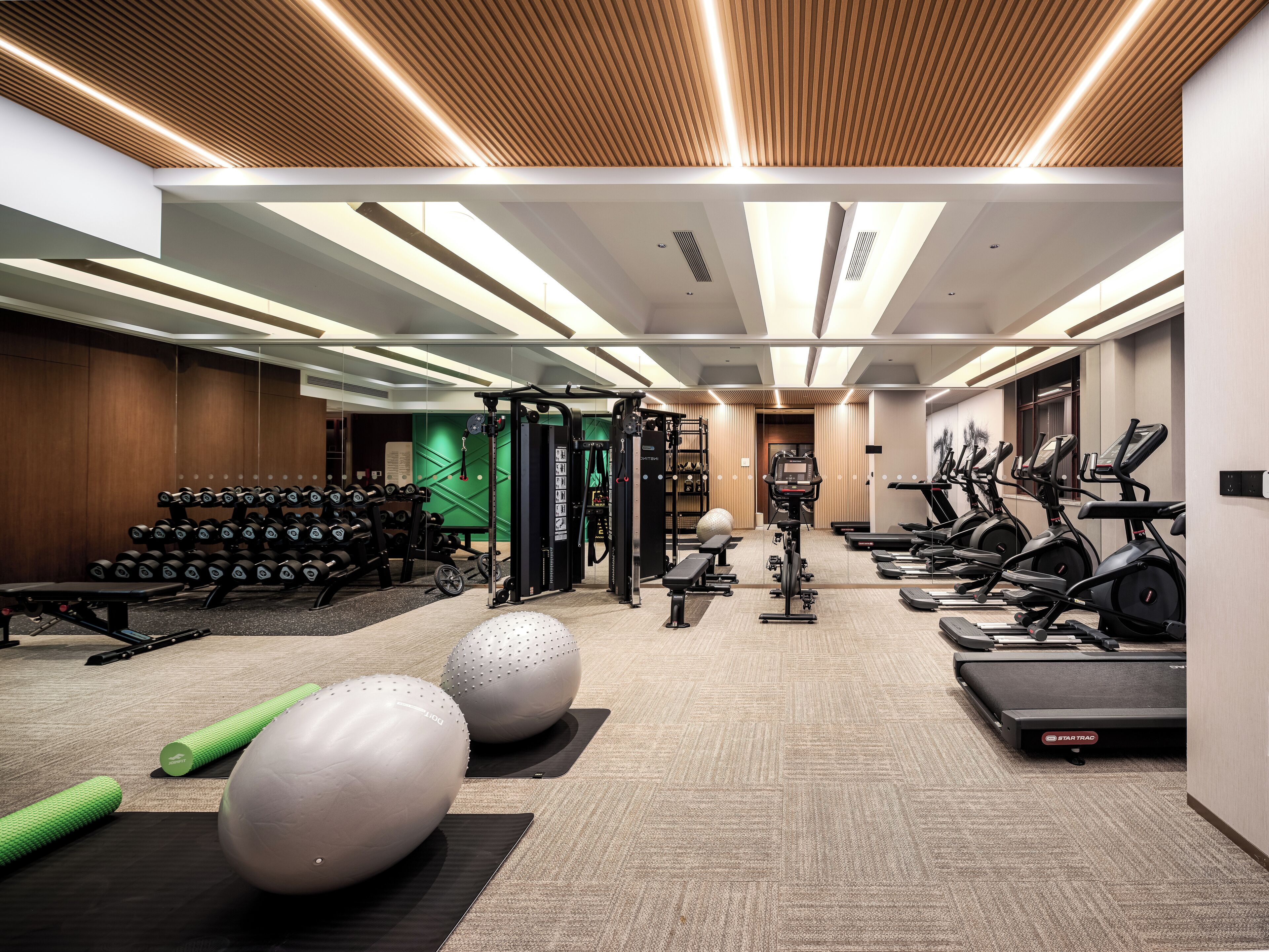 A modern gym with various exercise equipment, including treadmills, elliptical machines, and free weights.