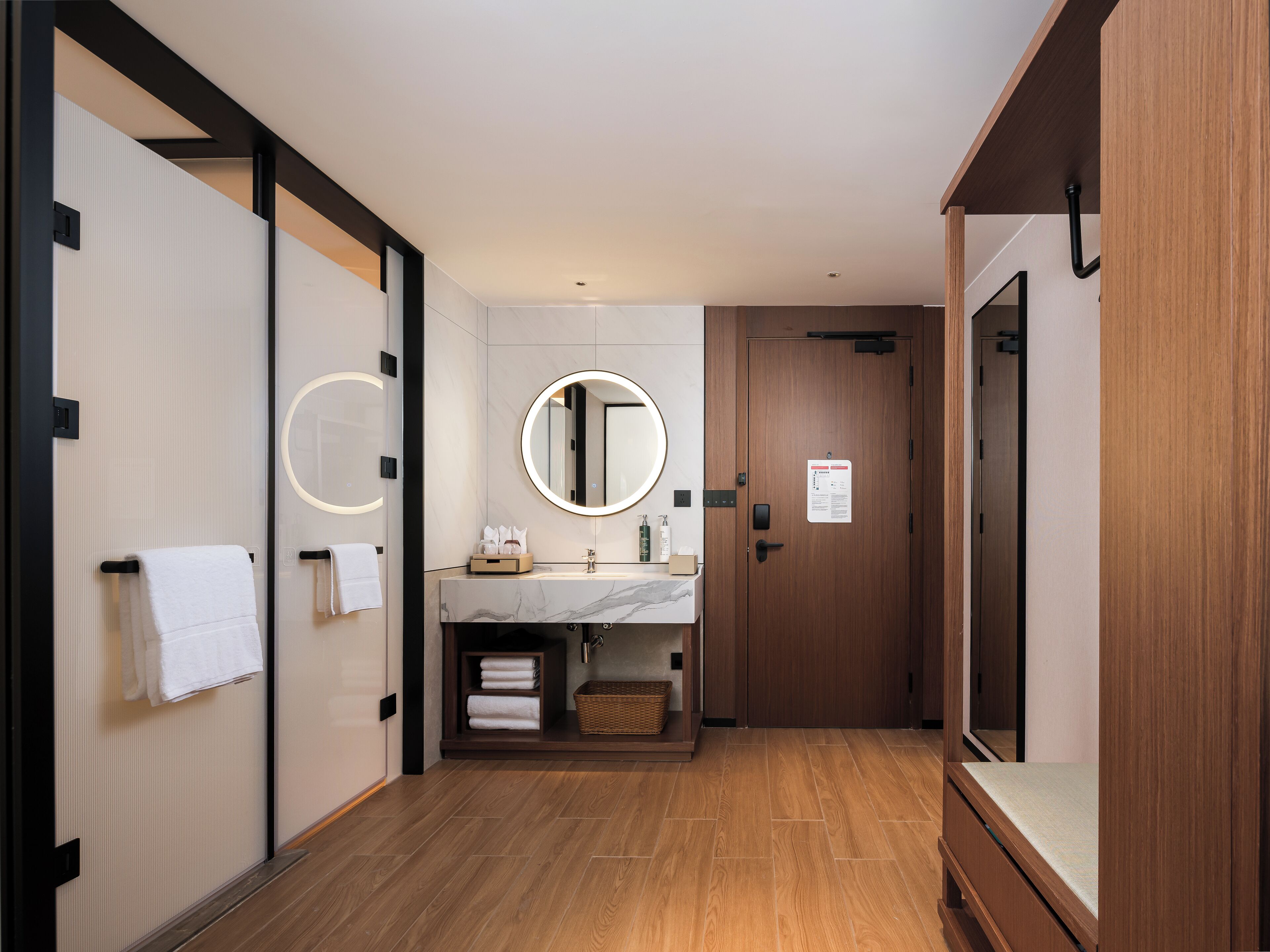 A modern bathroom with a wooden floor, a marble sink, and a large mirror.