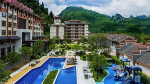 A hotel with a swimming pool, children's play area, and traditional architecture. - Hilton Garden Inn Zhangjiajie Wulingyuan (Zhangjiajie)