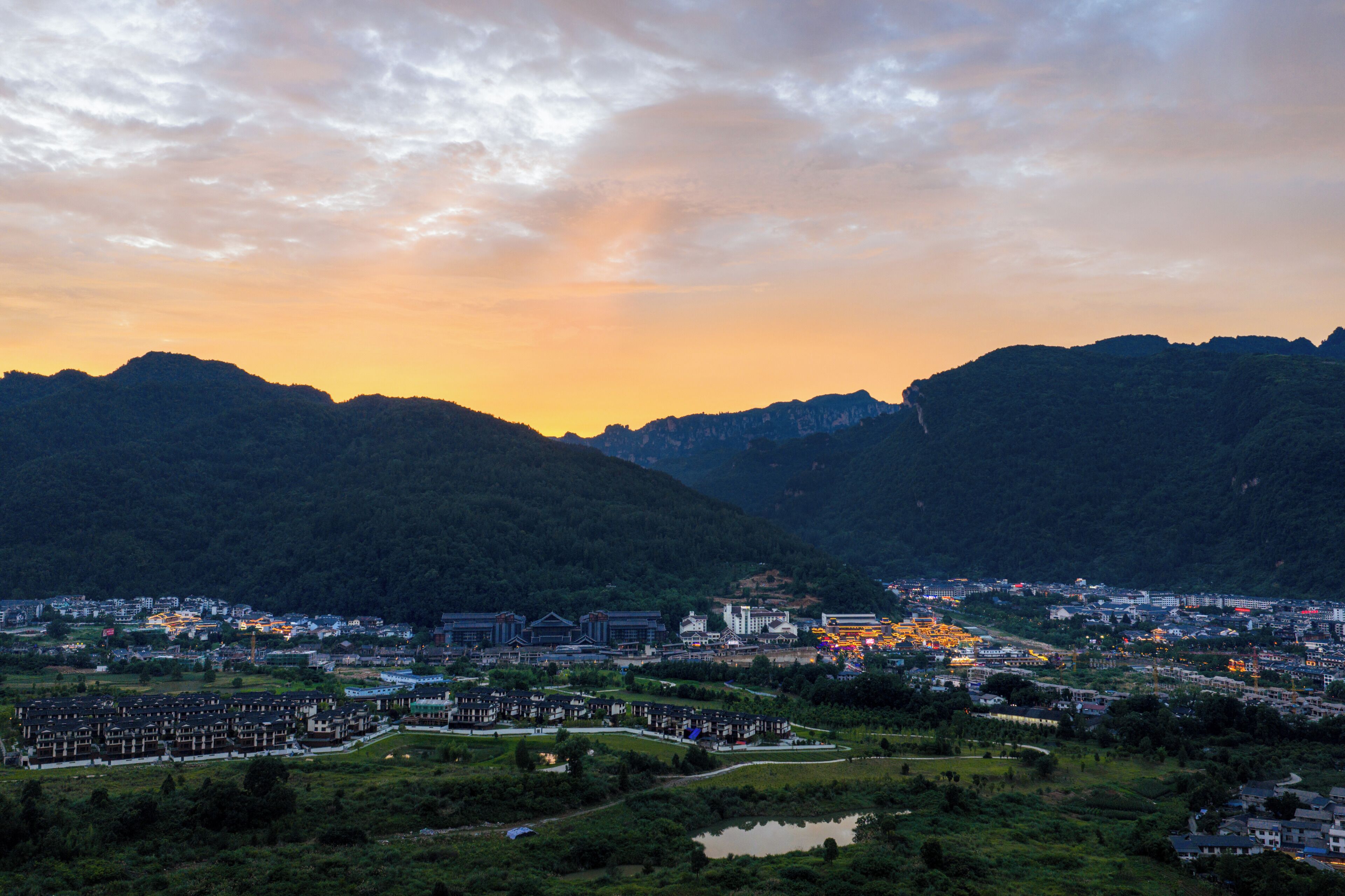 A town with a river, buildings, and mountains in the background.
