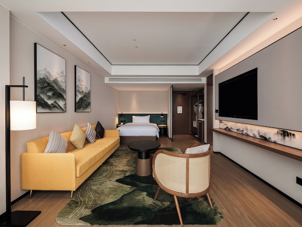 Una habitación de hotel moderna con sofá, cama, televisión y obras de arte en las paredes.