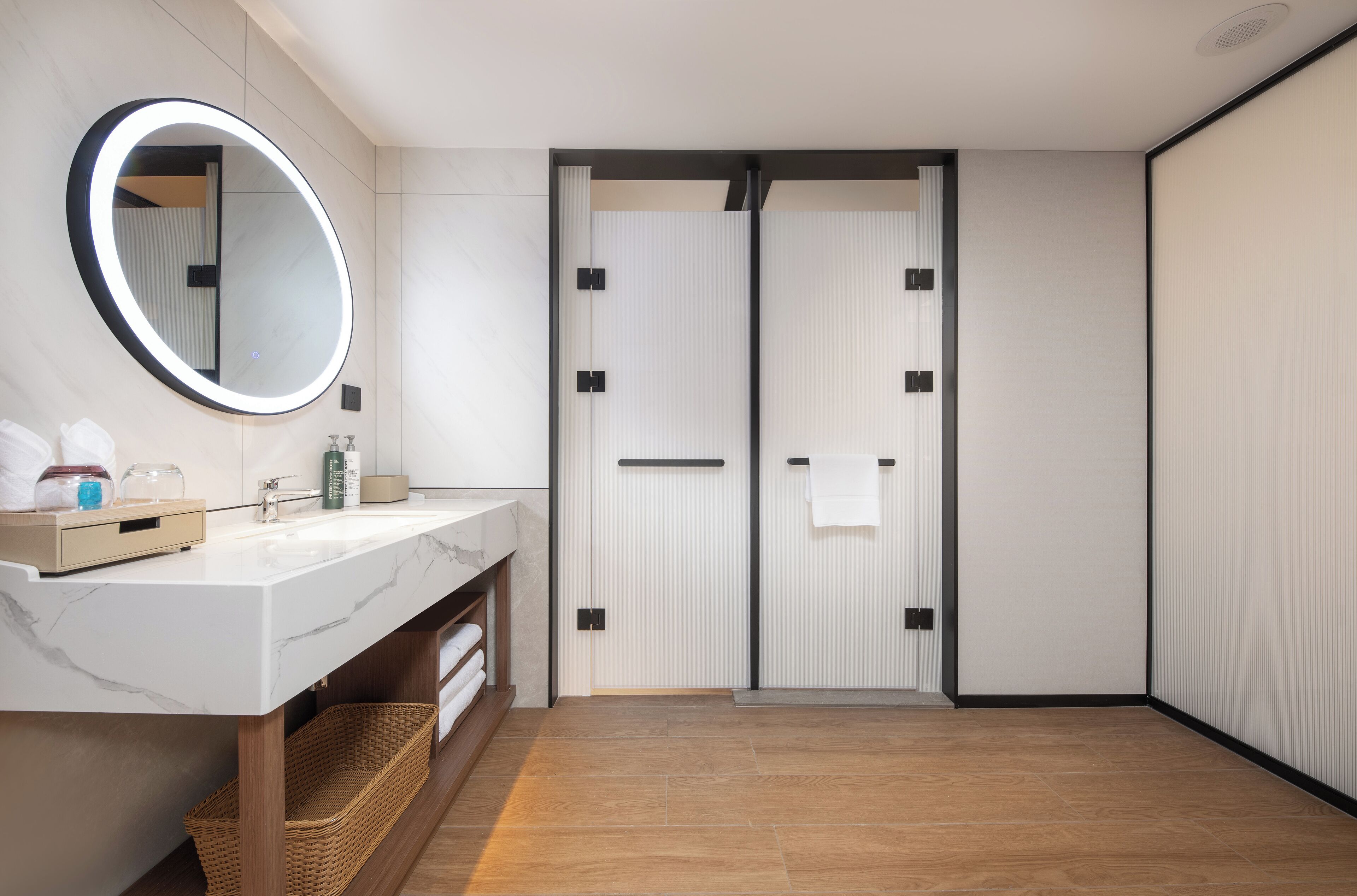 Une salle de bain moderne avec un lavabo en marbre, un grand miroir et un plancher en bois.