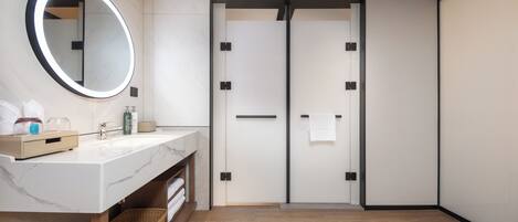 A modern bathroom with a marble sink, a large mirror, and a wooden floor.
