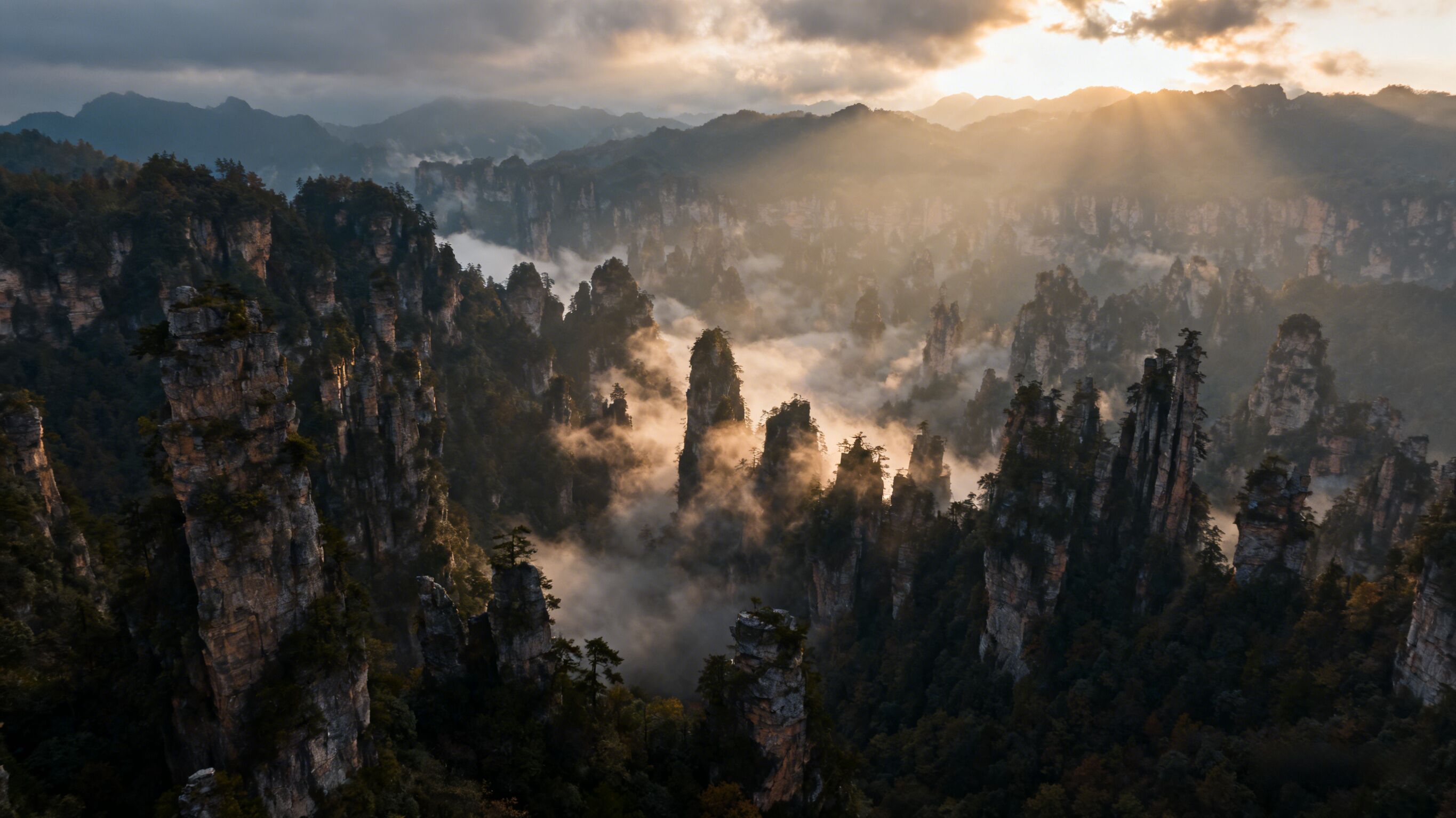 Un paisaje montañoso con altas formaciones rocosas y un denso bosque.