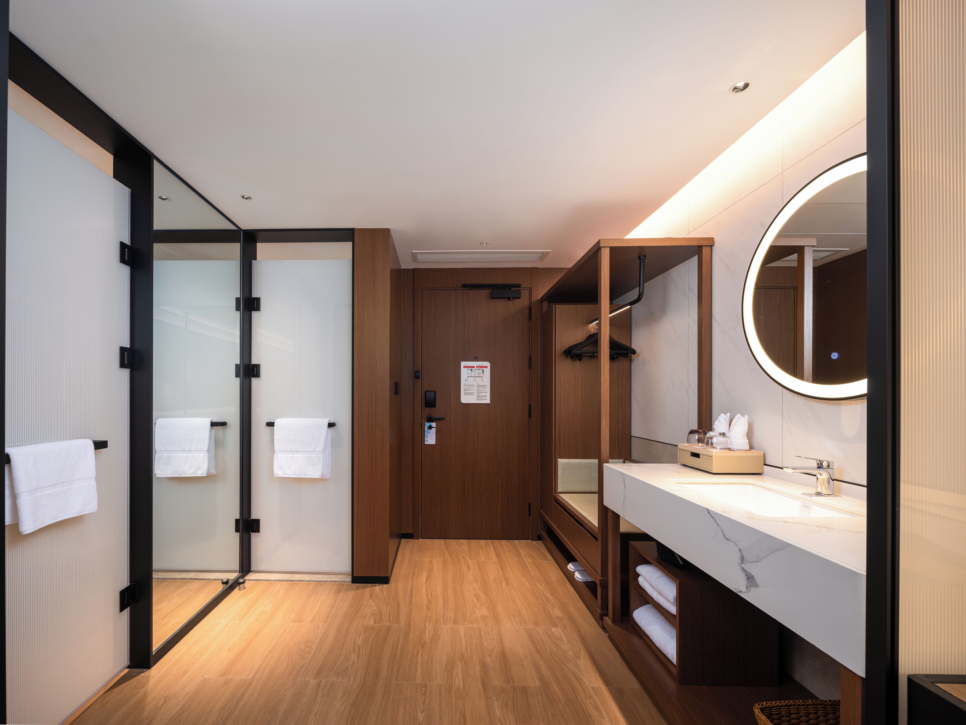 Un baño moderno con suelo de madera, un espejo grande y un lavabo blanco.