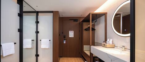 Un baño moderno con suelo de madera, un espejo grande y un lavabo blanco.