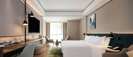 Una habitación de hotel moderna con una cama grande, un escritorio, un televisor y una zona de estar.