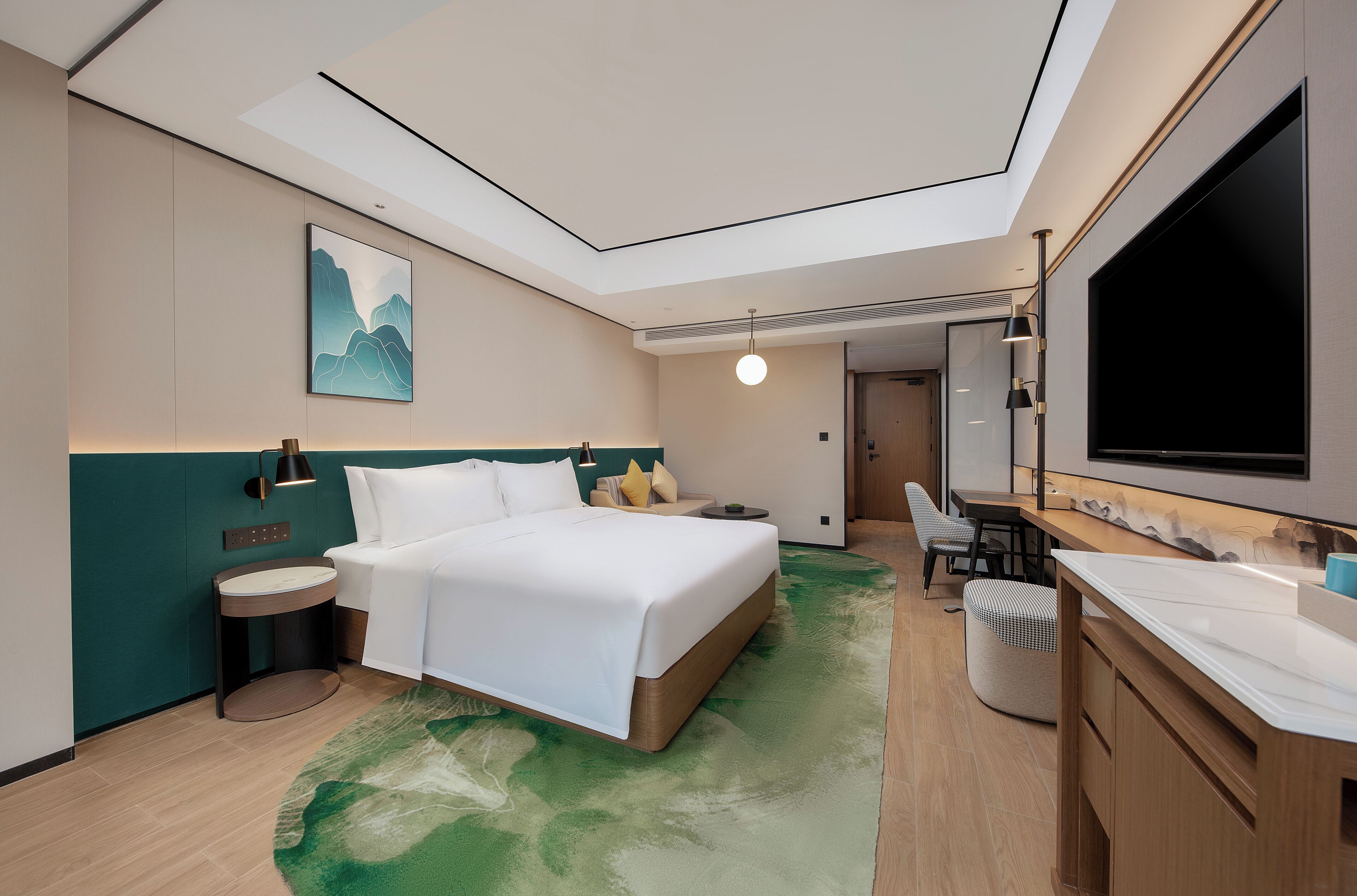 Una habitación de hotel moderna con una cama, mesita de noche, lámpara y un televisor grande.