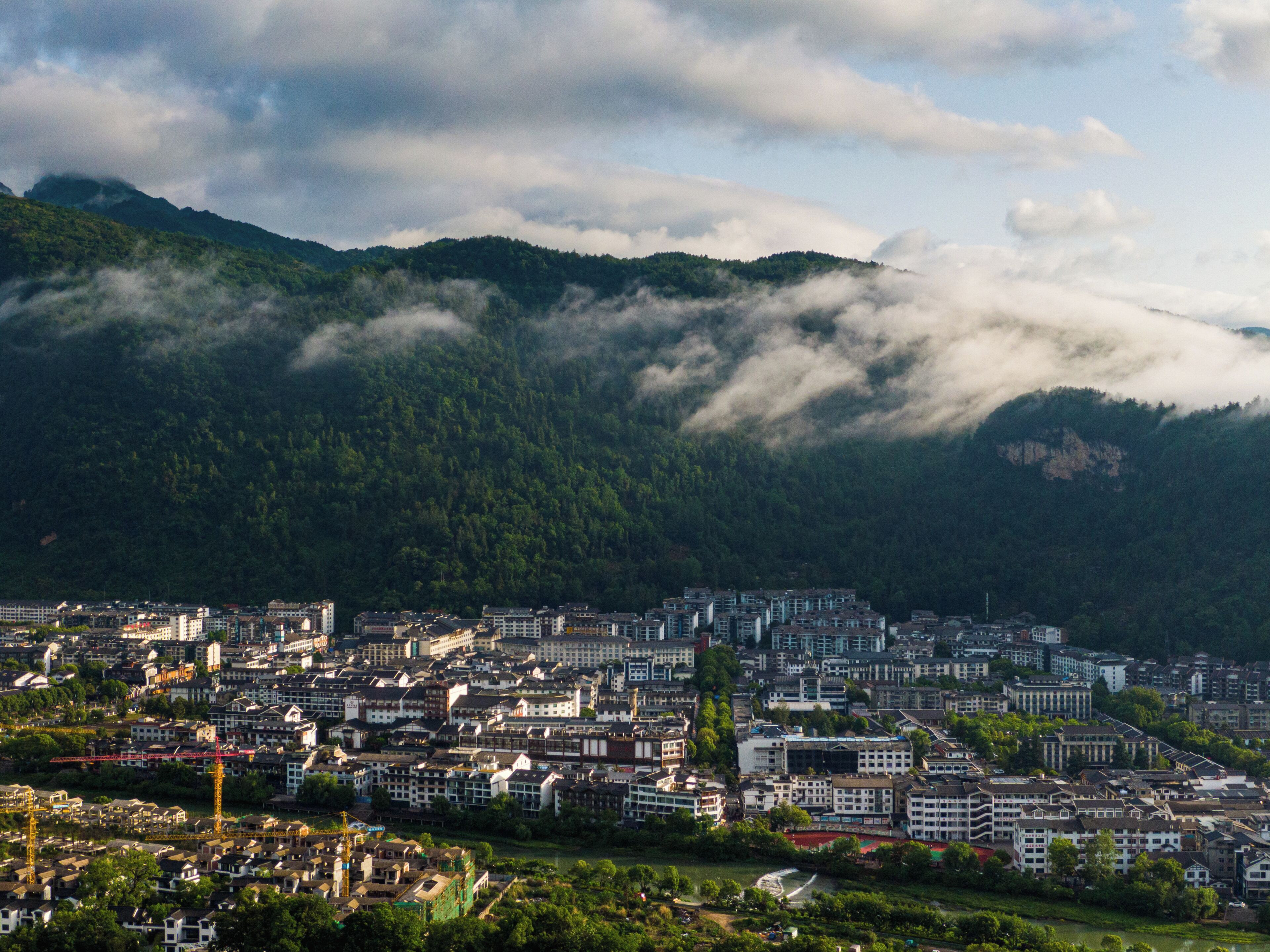 A cityscape with dense urban buildings, a river, and mountains in the background.
