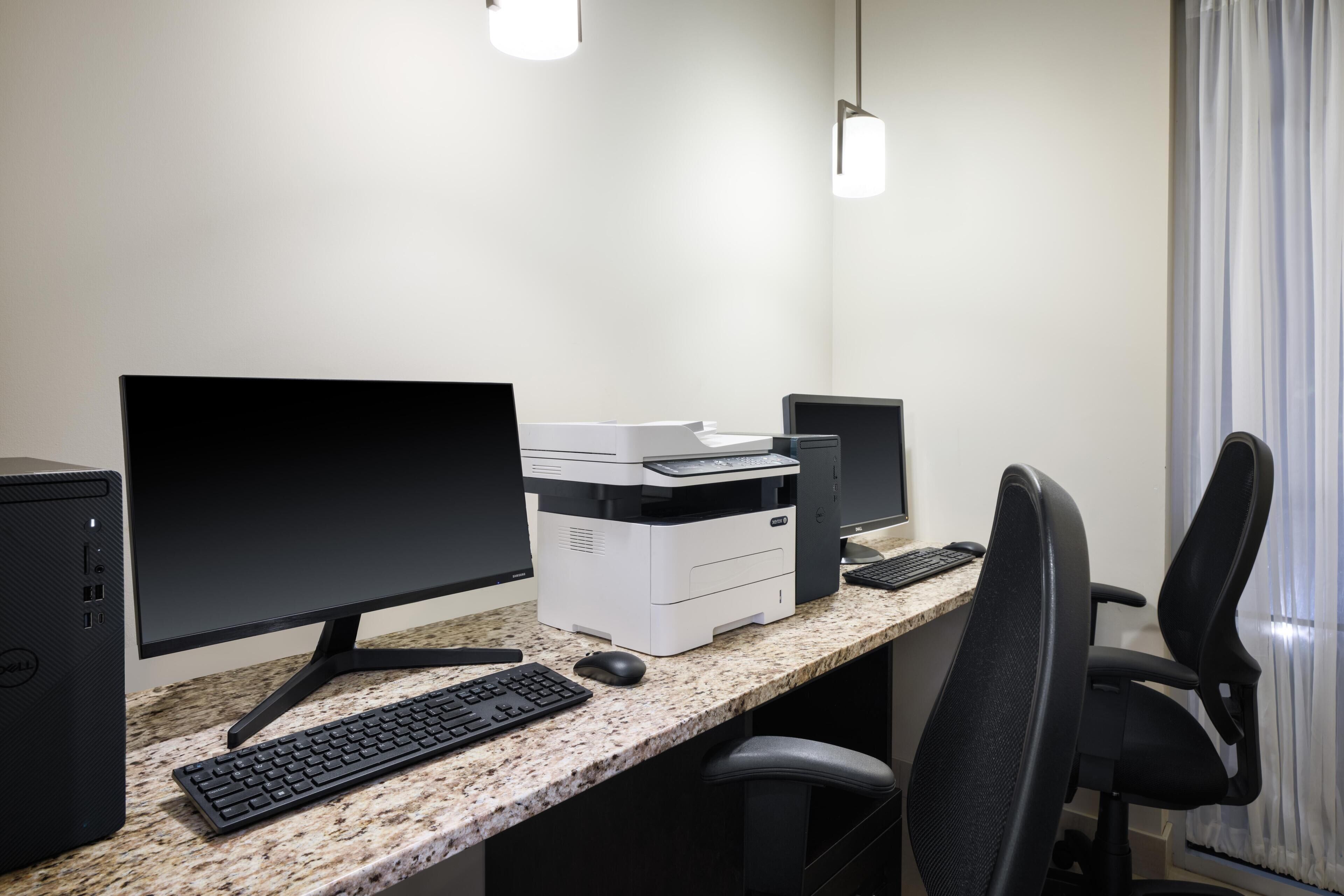 Un espacio de trabajo con computadora de escritorio, monitor, teclado, ratón, impresora y silla de oficina.