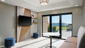 Una habitación moderna con televisión de pantalla plana, una mesa redonda, un sofá y un ventanal con vistas.