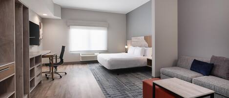 Una habitación de hotel moderna con cama, sofá, escritorio y armario.