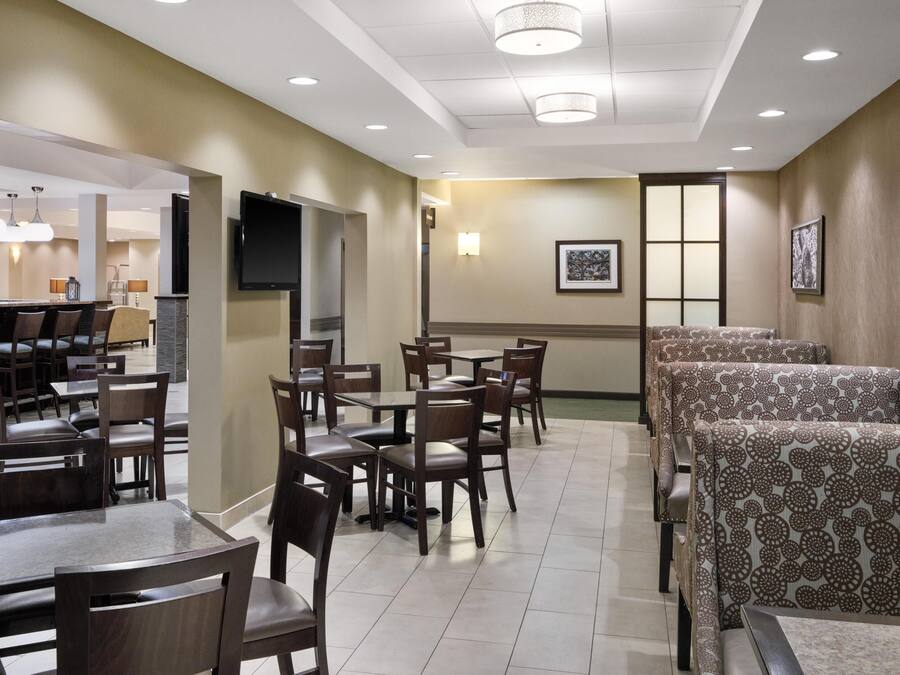 A hotel dining area with tables and chairs, a television, and framed artwork on the walls.
