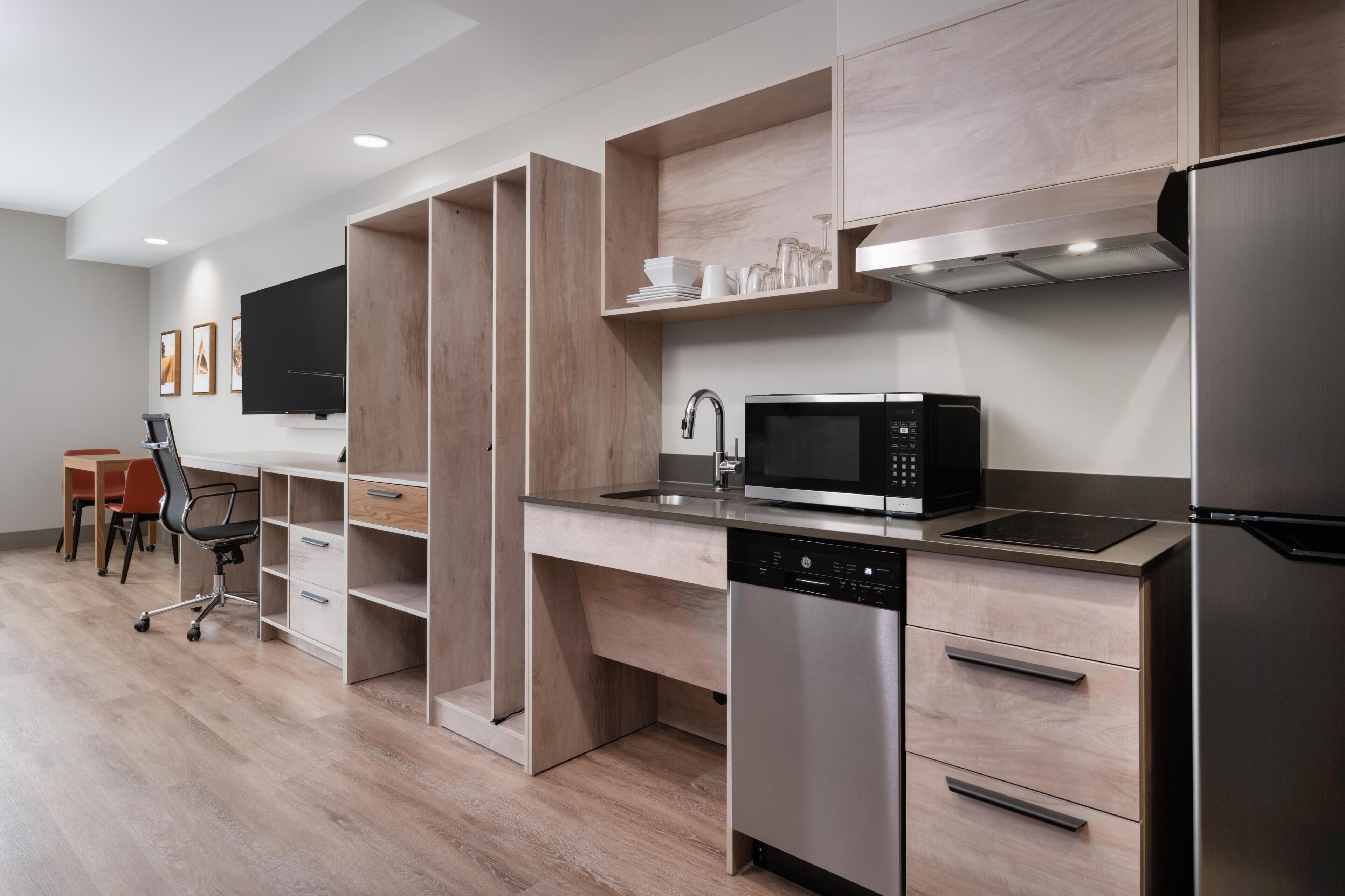 A modern kitchen with built-in appliances, wooden cabinetry, and a dining area with a table and chairs.
