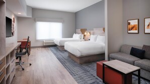 Una habitación de hotel con cama, sofá, escritorio y silla, y televisor.