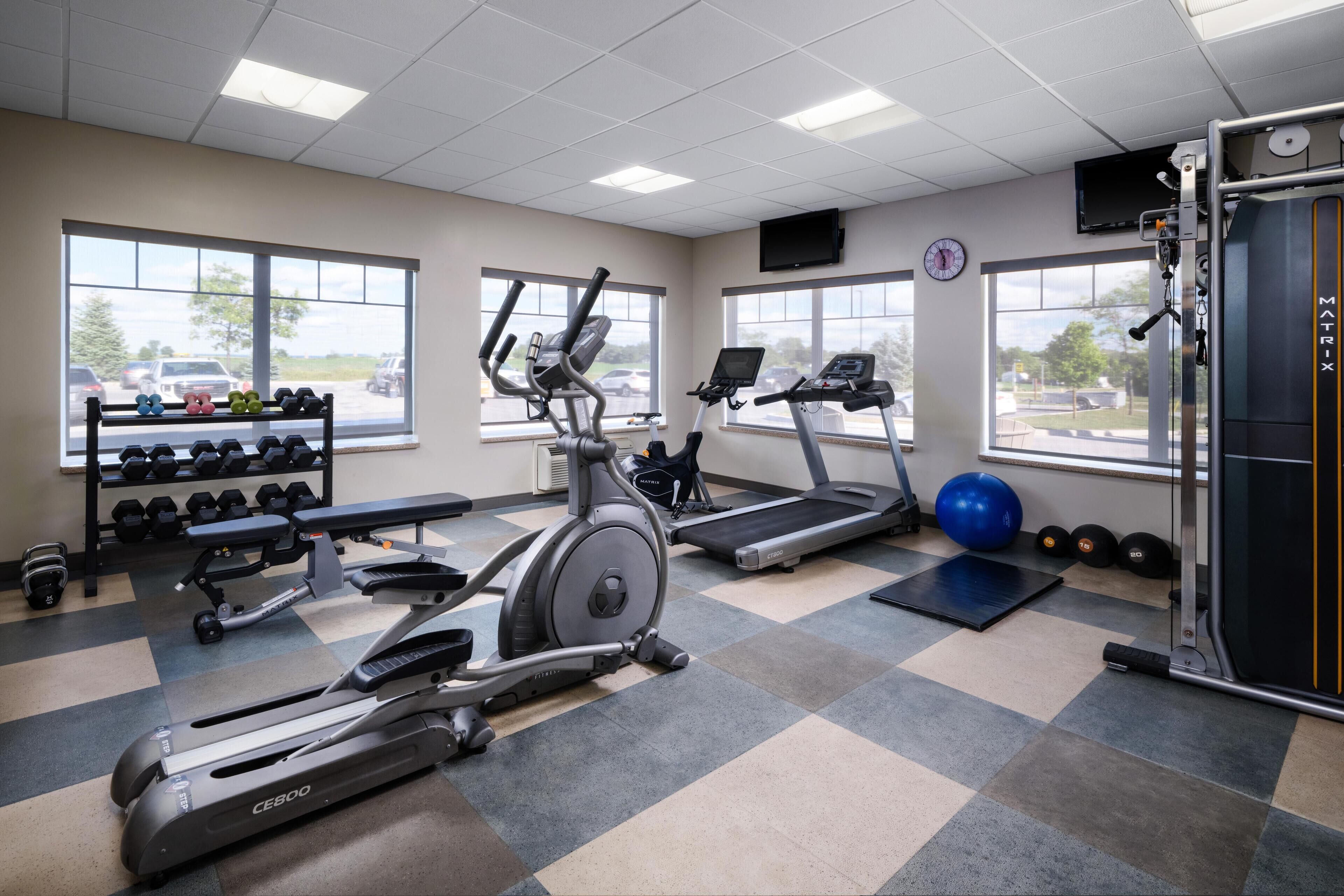 Une salle de sport équipée de tapis de course, d’un vélo elliptique, d’haltères et d’un vélo d’appartement.