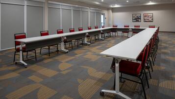 Ein Konferenzraum mit einem langen Tisch, roten Stühlen und einem gemusterten Teppich.